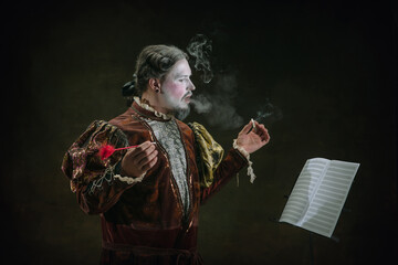 Creating and smoking. Young man as Johann Bach on dark green background. Retro style, comparison of...