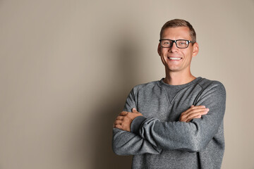 Man in stylish grey sweatshirt on beige background, space for text