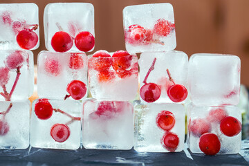 Melting ice cubes with frozen red berries inside them. Ice for refreshing drinks or beauty...