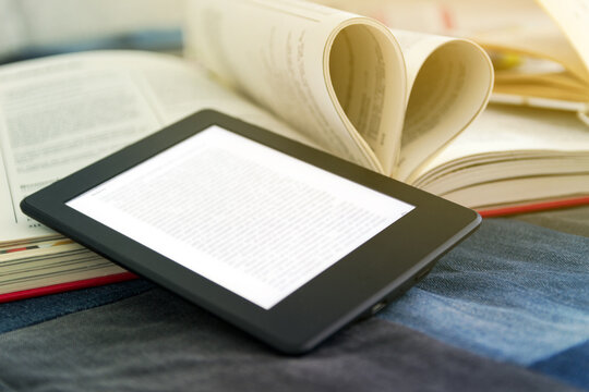 e-book concept of reading e-books. Book reader next to paper books.
