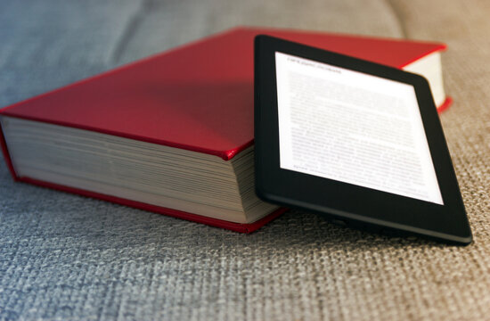 e-book concept of reading e-books. Book reader next to paper books.