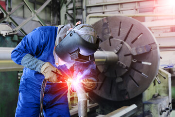 Workers welder welding by Tig gas argon on steel pipe line fabrication in factory on old lathe is...