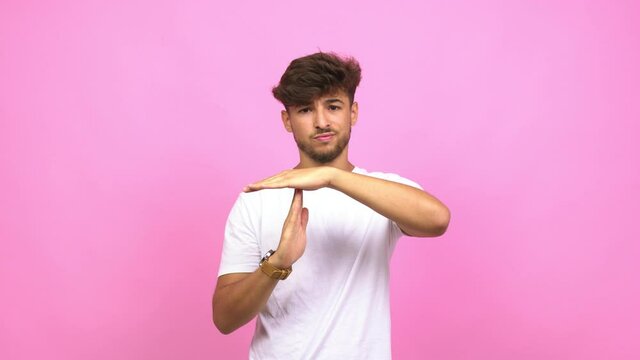 Young arab man tired and bored, doing a timeout gesture, needs to stop because of work stress, time concept