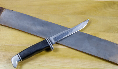 Used Hanging Razor Strop and hunting  knife on wood textured board
