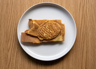 Taiyaki Japanese filled fish shaped pastry cake  on plate. Commonly filled with bean paste, custard, or sweet potato with a waffle like batter.