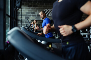 Fototapeta na wymiar Young man in sportswear running on treadmill at gym.