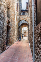 Fototapeta na wymiar Narrow medieval street with motorcycles in San Gimignano, Italy