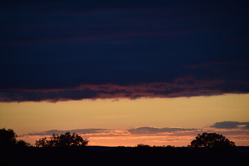 Paisaje de atardecer en el campo con nubes y árboles
