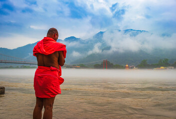 view of River Ganges, the famous bridge Ram Jhula surrounded by temples and mountains around in...