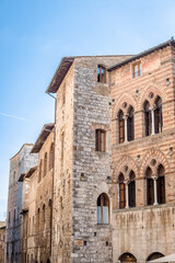 Fototapeta premium Medieval building with windows in the Venetian style on the central square Piazza Della Cisterna in San Gimignano, Italy