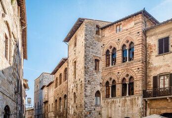 Fototapeta premium Old houses of different ages and styles merged into one wall on Piazza Della Cisterna in San Gimignano, Italy