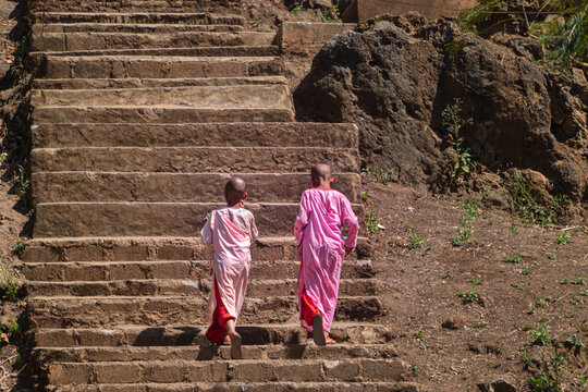 Two Little Buddhist Nuns Running Up The Stairs.