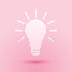 Paper cut Light bulb with rays shine icon isolated on pink background. Energy and idea symbol. Lamp electric. Paper art style. Vector.