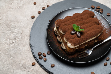 Classic tiramisu dessert on ceramic plate on concrete background