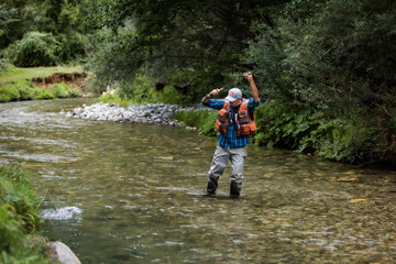A fly fisherman fishing a trouts in mountain river