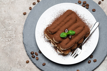 Classic tiramisu dessert on ceramic plate on concrete background