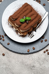 Classic tiramisu dessert on ceramic plate on concrete background