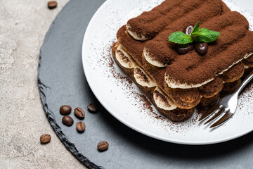 Classic tiramisu dessert on ceramic plate on concrete background