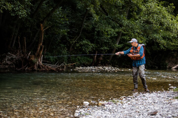 Fototapeta na wymiar A fly fisherman fishing a trouts in mountain river