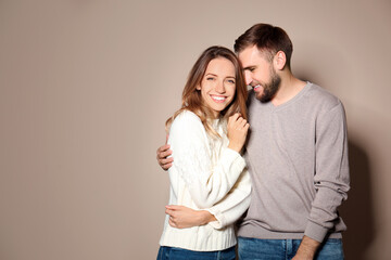 Lovely couple in warm sweaters on beige background. Space for text
