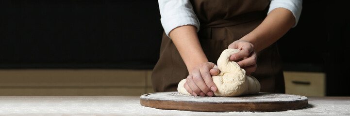 Baker kneading dough at table, closeup with space for text. Banner design