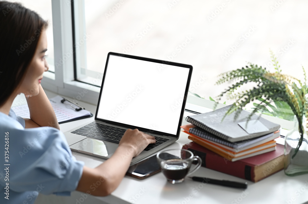 Poster a close-up image of a woman is using a computer laptop at the white working desk.