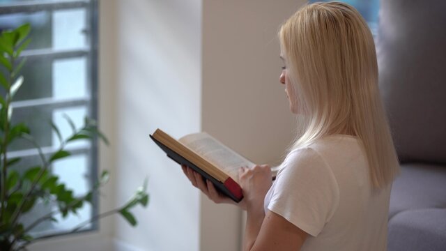 Young Woman Praying While Holding Bible. Woman With Bible Praying And Reverencing God In Her Daily Devotional At Home. 4k