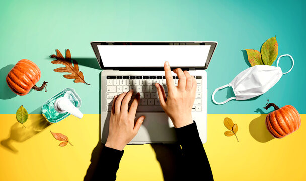Person using a laptop computer with a mask and a sanitizer bottle in Autumn