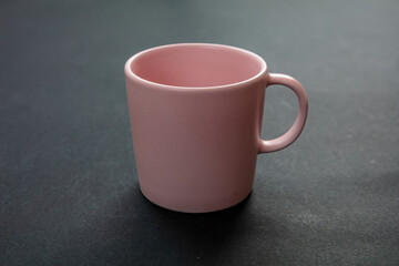 Coffee mug pink color on black background. Hot beverage cup mockup template