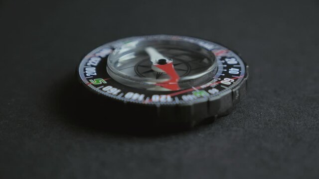 Extreme close up of a transparent modern compas on black background. Concept of travel, adventure, expedition 4k