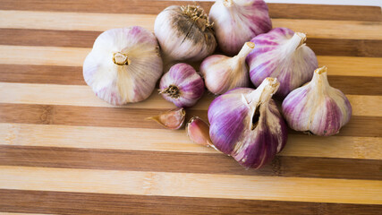 Beautiful, fresh and young garlic is plucked from the garden and lies on a wooden plank.