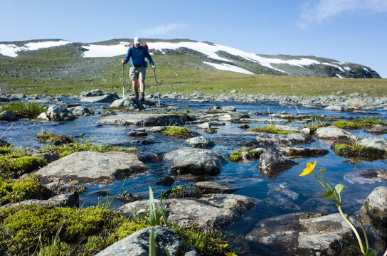 Hiking in Swedish Lapland. Mountain nature of Scandinavia in summer sunny day. Man crossing river blured on background, Trekking on Nordkalottruta or Arctic Trail in northern Sweden
