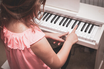 Girl learning to play piano at home on elctric piano in the bedroom
