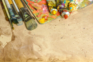 Tubes of multicolor oil paint and artist's brushes on canvas close-up.