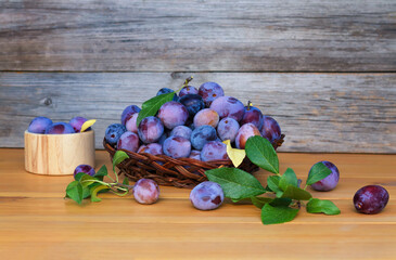 Plums in a vase on a wooden background. 