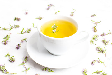 A Cup of tea with thyme flowers on a white background. The view from the top. Concept of folk medicine. Herbal drink.