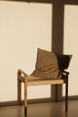 Pillow on wicker bench in sunlight shadows on the wall. Minimal interior design concept