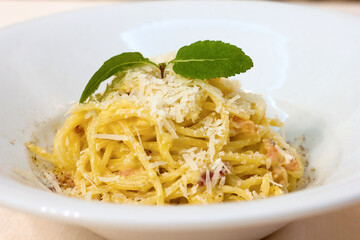 Macaroni pasta with grated parmesan cheese and a sprig of greens close-up on a white plate