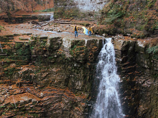 Fototapeta premium man with woman holding ukrainian flag on the top of the waterfall