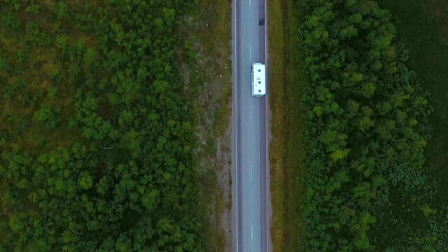 Aerial view above a caravan rv driving on a asphalt road, in arctic wilderness, rainy, summer day, in Norbotten, Lappland, Finland - OIverhead drone shot
