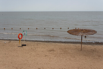 Obraz premium Empty beach on a cloudy cool day. The inscription on the lifebuoy 