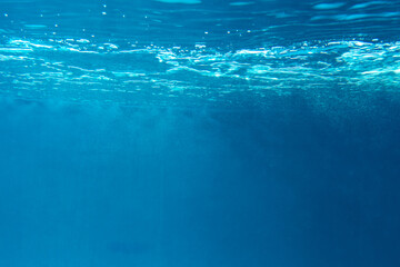 Summer. Texture of water surface. Underwater background. Waves effects. Blue underworld. Ocean, sea. Diving. Blue sea pool water. Bottom view.