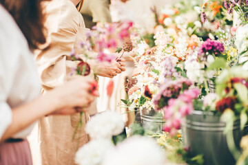 Young women choose different fresh colorful flowers growing in modern greenhouse at interesting floral masterclass on sunny autumn day close view