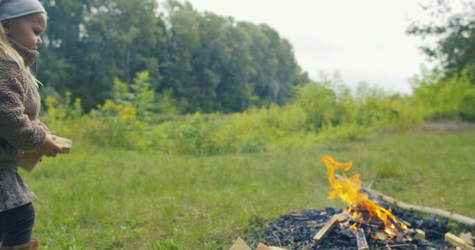 Dziewczynka bierze drewno i rzuca w ogień