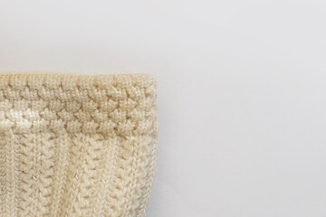 Winter knitted hat. Fragment of a white woolen hat. White background. Close-up. Coarse knit texture. Winter mood. Gift for the new year