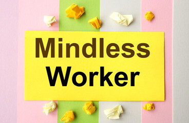 MINDLESS WORKER. text on colorful background. near the crumpled pieces of paper