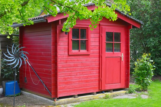 Rot gestrichenes Gartenhaus aus Holz an einem ländlichen Einfamilienhaus, Hessen, Deutschland