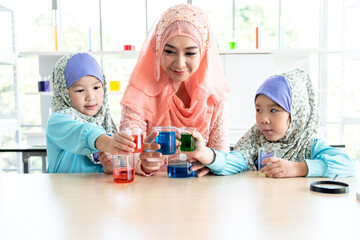 Muslim teachers wearing Islamic clothes are teaching Muslim children about scientific experiments in the laboratory, to education and science concept.