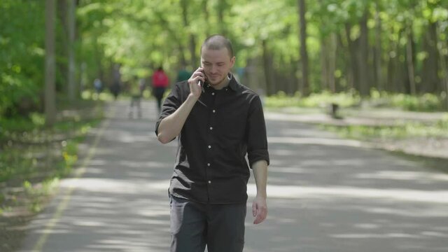 Stay in touch. Portrait of a young stylish walking man in a Park, with a phone in his hands and emotions on his face. Soft focus