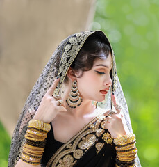 Portrait of beautiful young asian Thai girl with black and gold traditional India dress.